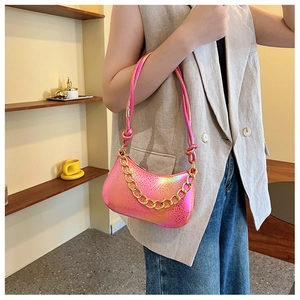 Detailed close-up of metallic pink shoulder bag with thick gold chain and knot strap