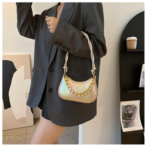 Iridescent gold baguette bag with scale texture and chunky gold chain on grey blazer