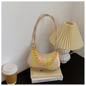 Detail of gradient snakeskin bag with chunky gold chain on white books background