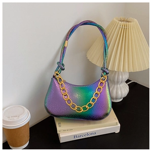Detail shot of a gradient hobo bag with gold chain and knot handle on books