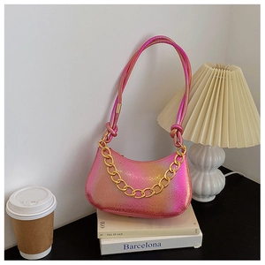 Detail of gradient pink-orange shoulder bag with gold chain on a minimalist indoor set