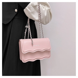 Detail of pink crossbody bag with scalloped flap and silver metal chain strap