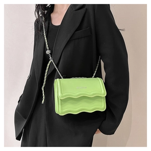 Detail of lime green crossbody bag featuring wavy edges and silver chain strap
