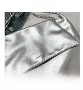 Détail d'un sac bandoulière en cuir argenté métallisé avec chaîne et texture gaufrée
