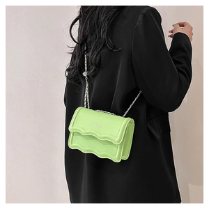 Detail of lime green leather bag with wavy flap design and silver chain strap