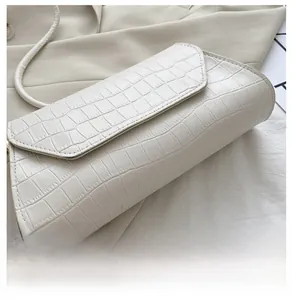 Close-up of white crocodile embossed leather handbag featuring detailed texture and strap