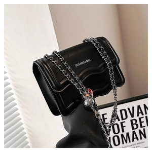 Detail of black faux leather flap bag with silver chain strap and metal ball charm