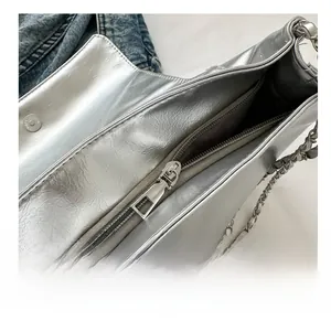 Détail du sac en cuir métallisé argenté avec fermeture éclair fluide et bandoulière
