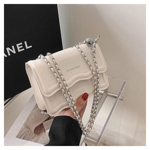 Detail of cream crossbody bag with wavy flap and silver adjustable chain strap