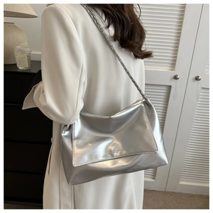 Détail du sac bandoulière argenté en cuir souple avec chaîne tissée et logo embossé