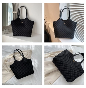 Detail of black quilted tote bag with golden logo and textured diamond stitching
