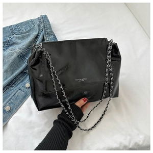 Détail du sac cabas en cuir verni noir avec bandoulière chaîne argentée et lettrage