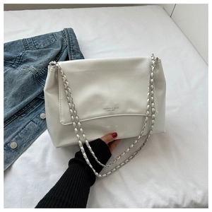 Détail du sac cabas en cuir blanc avec texte embossé et bandoulière en chaîne argentée