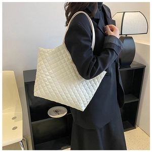 Detail of white quilted tote bag with diamond pattern and slim shoulder straps