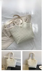 Close-up of white quilted tote bag featuring a golden clover-shaped metal buckle detail