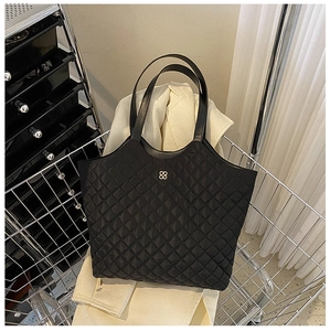 Close-up of black quilted tote bag with diamond stitching and small gold flower logo