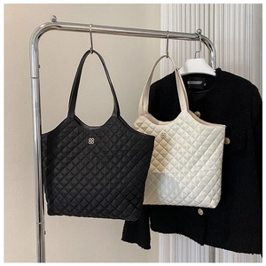 Detail of quilted diamond pattern and metallic logo on black and beige tote bags