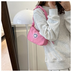 Détail du sac rose avec patch cœur dentelle, motif lapin et bandoulière plissée chic