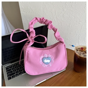 Détail du sac croissant rose plissé avec écusson lapin mignon et décoration nœud