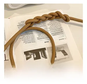 Detail view of brown PU leather bag featuring a chunky twisted knot braided shoulder strap