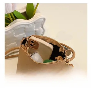 Detail showing inner capacity of brown leather crossbody bag with smartphone and charm