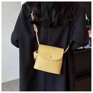 Detailed back view of a bright yellow textured leather crossbody bag with a leaf charm
