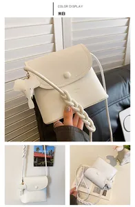 Detail of off-white leather crossbody bag with braided strap and cute elephant pendant