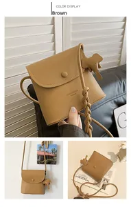 Close-up of brown litchi grain PU leather bucket bag with cute elephant charm and flap