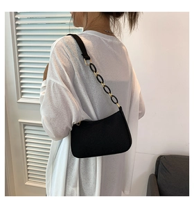 Close-up of black baguette bag with mixed gold and black metal chain shoulder strap