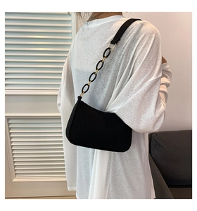 Detail of a black underarm bag featuring a unique black and gold chain link strap