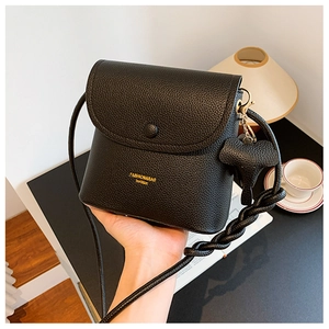 Close-up of black litchi leather crossbody bag with a cute elephant pendant detail