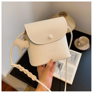 Close-up of beige crossbody bag featuring braided strap and cute elephant charm detail