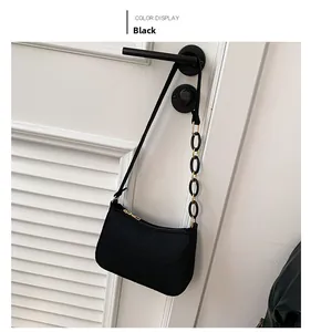 Close-up of black crossbody bag featuring pleated texture and gold-accented chain detail
