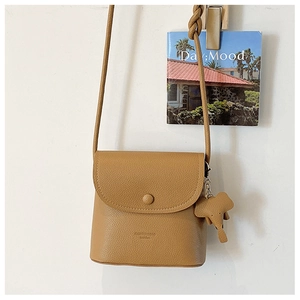 Detail of khaki crossbody bag featuring lychee grain texture and a cute elephant charm