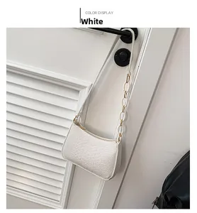 Detail of white baguette bag with crocodile texture and chunky chain on door handle