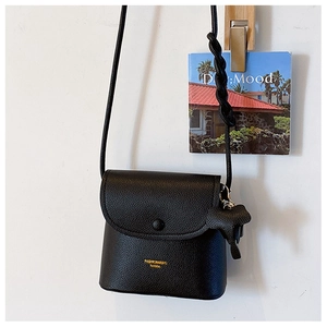 Detail view of black pebble leather bucket bag with woven strap and horse charm