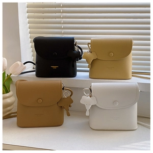 Row of mini crossbody bags in four colors with matching elephant charms on a white ledge