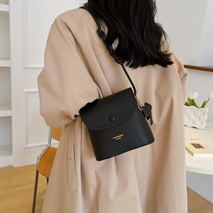 Minimalist black pebbled leather crossbody bag with woven strap and animal pendant