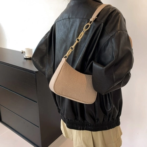 Minimalist beige underarm bag with thick chain strap shown on a model's shoulder