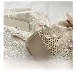 Close-up of precise stitching on a beige bucket bag with embroidery and straw texture