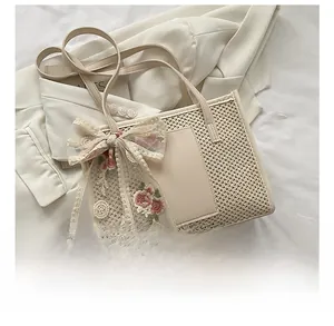 Detail of straw tote bag featuring floral lace bow embroidery and leather handles