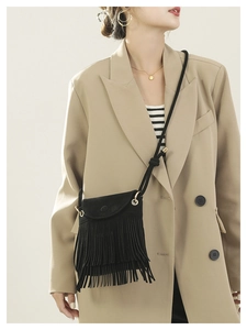 Détail d'un sac bandoulière noir à franges en daim mat porté par un mannequin