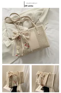 Detail of cream straw tote bag featuring intricate lace embroidered bow and chic scarf