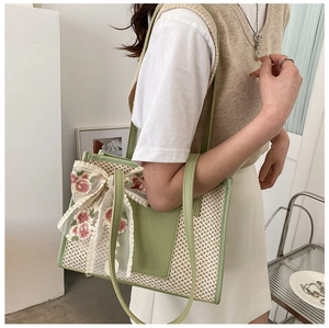 Green woven tote bag with white lace bow and floral embroidery shown on shoulder