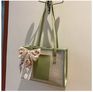 Detail of straw tote bag featuring white lace bow and pink floral embroidery accents
