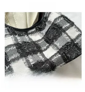 Close-up of black and white checkered fabric with frayed edge tassels and textured weave
