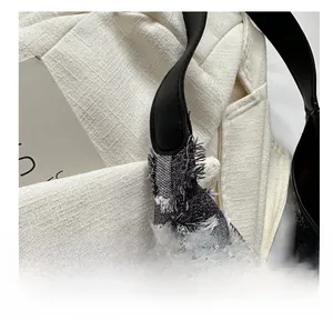 Close-up of black and white tweed tote bag with fringe edges and leather handles