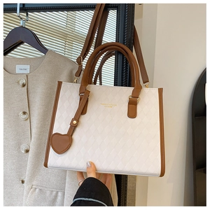 Close-up of diamond quilted white leather tote with brown straps and gold lettering