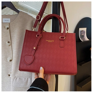 Detail of dark red quilted leather handbag with heart pendant and gold hardware