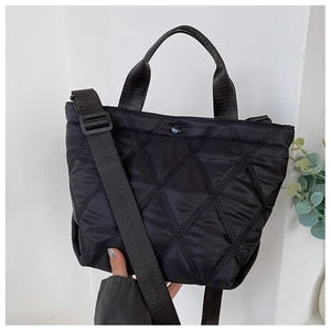 Detail der schwarzen gesteppten Nylon-Beuteltasche mit Rautenmuster und breitem Gurt